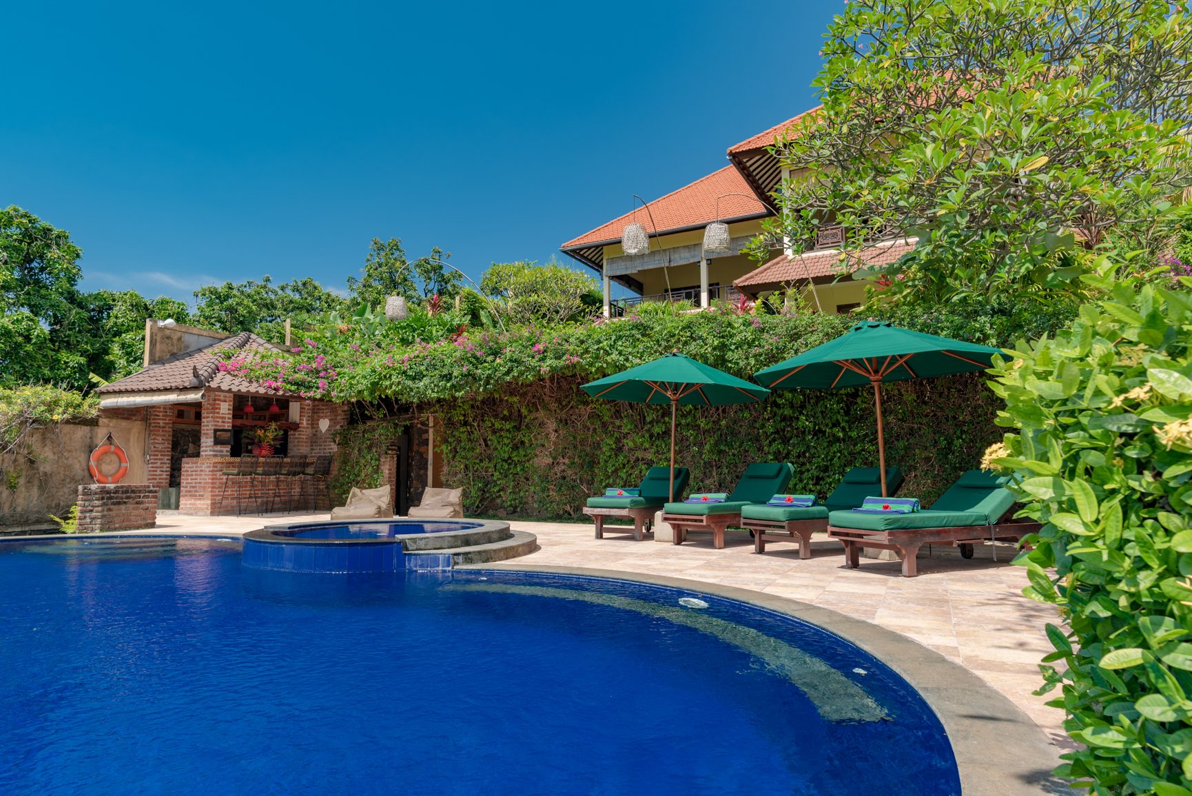 Alamanda Lovina Resort buildings and pool seen across the tropical garden