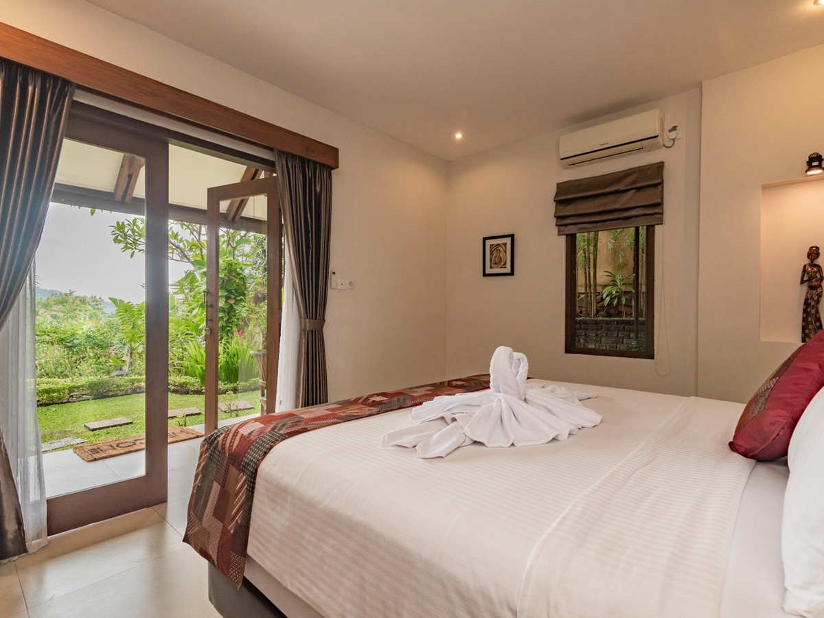Bedroom of Suite Kupu Kupu at Alamanda with a king bed and tropical garden view